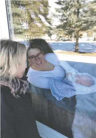  ??  ?? Lori Newlove visits with her daughter, Rylee, and grandson, Brooks, through the front window of Rylee’s home in Waldheim. This Mother’s Day, physical distancing means families may have to get creative to celebrate.