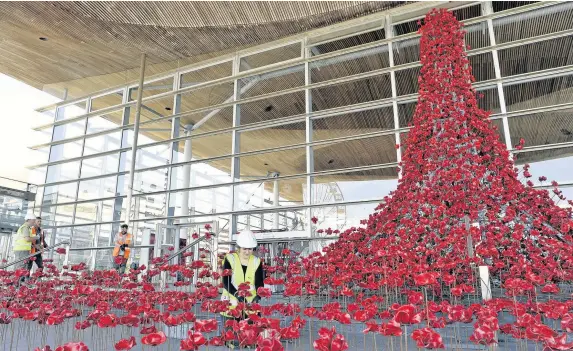  ??  ?? > A cascade outside the Senedd comprising several thousand handmade ceramic poppies was originally seen at the Tower of London