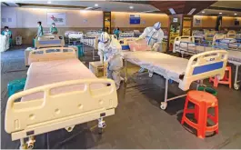  ?? — PTI ?? Workers, wearing PPE, prepare beds inside an isolation ward for Covid-19 patients at Jawaharlal Nehru Marg in New Delhi on Monday.