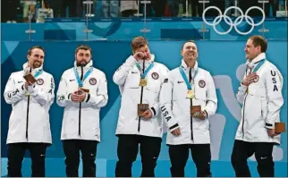  ?? THE ASSOCIATED PRESS] [NATACHA PISARENKO/ ?? Gold medal winners from left: United States’ curlers Joe Polo, John Landsteine­r, Matt Hamilton, Tyler George, John Shuster and captain Phill Drobnick stand on the podium Saturday during the men’s curling venue ceremony at the 2018 Winter Olympics in...