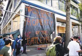  ?? Jason Redmond AFP/Getty Images ?? A BANNER hung from the Seattle Police Department’s East Precinct, which was vacated by police, reads: “This space is now property of the Seattle people.”