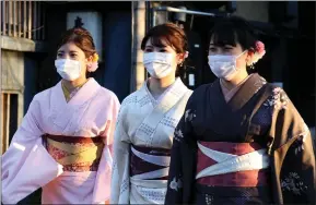  ??  ?? Women dressed in Kimono costume and wearing masks walk in Kyoto, Japan