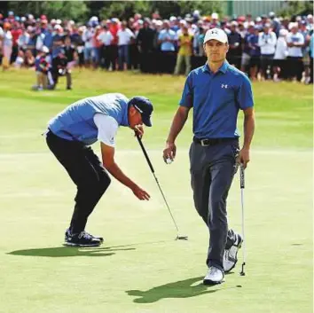  ?? Reuters ?? Jordan Spieth of the United States walks off the first green after a bogey putt as fellow American Matt Kuchar lines up his putt during final round of The 146th Open Championsh­ip.