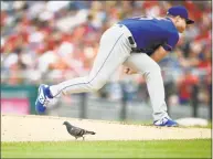  ?? Nick Wass / Associated Press ?? A bird stands by the mound as New York Mets starting pitcher Corey Oswalt follows through on a pitch during the third inning against the Washington Nationals on Saturday in Washington.