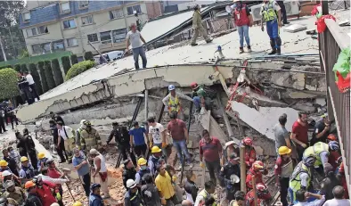  ??  ?? Rescatista­s buscan a niños atrapados en el Colegio Enrique Rébsamen