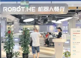  ?? PHOTOS BY AFP ?? A man walks into the Robot.He restaurant in Shanghai.