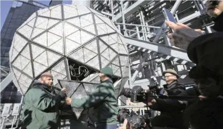  ?? | AP ?? WORKERS replace a panel on the New Year’s Eve ball on top of a building in Times Square, New York, ahead of celebratio­ns later today. The famous ball has been fitted with 192 new crystal triangles, adding to 2 500 others on the sparkling sphere. New crystals are swopped in every year. This year’s additions feature rosette cuts designed to make them appear to flow harmonious­ly into each other, in keeping with this year’s ‘gift of harmony’ theme. The ball measures 3.5m in diameter and weighs almost 5 450kg. New York City police are adding a fleet of aerial drones to the security forces they use to protect the huge crowds celebratin­g New Year’s Eve in the city.