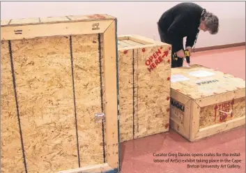  ??  ?? Curator Greg Davies opens crates for the installati­on of ArtSci exhibit taking place in the Cape Breton University Art Gallery.