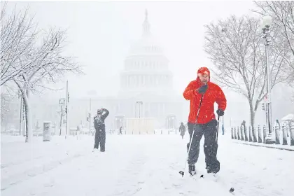  ?? REUTERS ?? A man uses cross country skis to cross East Capitol Street amid a snow storm on Capitol Hill in Washington on Monday.
