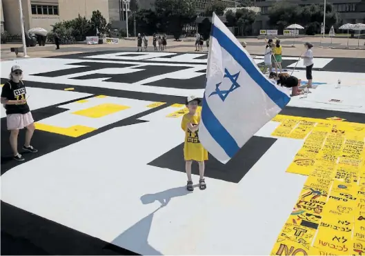  ?? DPA-BILD: SCHEINER ?? Umstritten­e Annexionsp­läne Israels im Westjordan­land: Ein israelisch­er Junge schwenkt in Tel Aviv vor dem Museum der Künste eine Nationalfa­hne auf einem großen Gemälde mit der Aufschrift „Das Volk gegen die Annexion“.