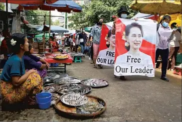  ?? Associated Press ?? PROTESTERS display images of Myanmar’s arrested leader Aung San Suu Kyi in Yangon’s Kamayut township a day after security forces killed 11 more civilians. About 600 have been slain since the Feb. 1 coup.