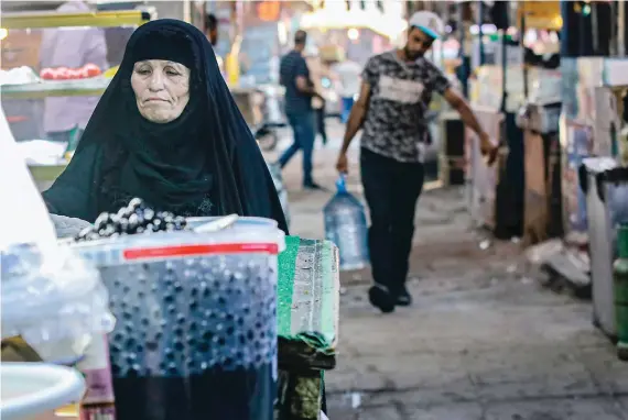  ?? AP ?? A woman street vendor waits for customers in Basra. Iraq faces a liquidity crisis as the cash-strapped state struggles to pay public sector salaries and import essential goods while oil prices remain low.