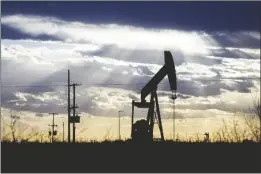  ?? ELI HARTMAN VIA AP ?? THE SUN SHINES through the clouds as it begins to set behind a pumpjack on March 30, 2022 outside of Goldsmith, Texas.