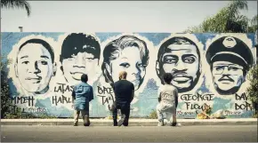  ?? Associated Press ?? Obba Babatund, portraying Daniel Harrison Sr., from left, Shemar Moore, portraying his son Hondo, and Deshae Frost, as Darryl, kneel in front of a mural in a scene from "S.W.A.T."