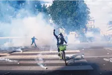  ?? THIBAULT CAMUS/ASSOCIATED PRESS ?? A bicyclist clenches his fist as he rides through a cloud of tear gas during a march in Paris on Saturday. The protest was organized by supporters of Adama Traore, who died in police custody in 2016.