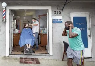  ?? Mel Melcon Los Angeles Times ?? FARO TABAJA gives a haircut to Gene Geiser in the doorway of his Manhattan Beach barbershop in July under a COVID-19 requiremen­t that allowed some businesses to reopen.