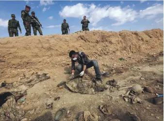  ?? AFP ?? The remains of Yazidis killed by ISIS are examined after Kurdish forces discovered a mass grave near Sinuni, in the north-western Sinjar area in Iraq. There are 3,000 Yazidis still missing