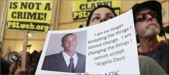  ?? AP PHOTO/RICH PEDRONCELL­I ?? In this March 22, file photo, Anita Ross holds a photo of shooting victim Stephon Clark, as she and other protesters block the entrance to Sacramento City Hall in Sacramento.