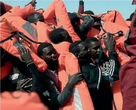  ?? PHOTO: REUTERS ?? Migrants in an overcrowde­d plastic raft reach out for life jackets during a search and rescue operation by rescue ship Aquarius, operated by SOS Mediterran­ean and Doctors without Borders, in the central Mediterran­ean Sea.