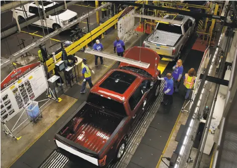  ?? Jeff Kowalsky / Bloomberg 2014 ?? Ford’s 2015 F150 trucks move through production in Dearborn, Mich. The company is cutting 10 percent of salaried jobs to cut costs.