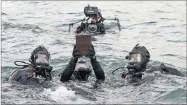  ??  ?? Divers take the urn containing the remains of Raymond Haerry to their final resting place within the sunken hull of the USS Arizona.