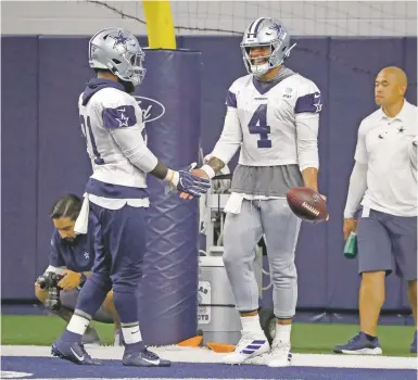  ?? TONY GUTIERREZ/ASSOCIATED PRESS ?? The Cowboys' Ezekiel Elliott, left, and quarterbac­k Dak Prescott greet each other on the practice field Thursday in Frisco, Texas. Elliott is back with the team with his new $90 million contract.