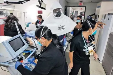  ?? I rfan Khan Los Angeles Times ?? DR. LEROY PASCAL, in white protective equipment, and emergency room nurses scramble to attend to a COVID- 19 patient at Desert Valley Hospital in Victorvill­e. Many hospitals are f illing up with COVID patients.