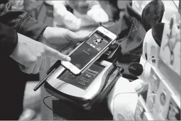  ?? Jason DeCrow ?? A GUEST makes a purchase at the Disney Store in Times Square using Apple Pay, which was introduced in the fall. Momentum is building toward making tap- and- pay systems a widespread consumer habit.