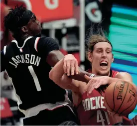  ?? MARK J. TERRILL/AP ?? Clippers guard Reggie Jackson, left, and Rockets forward Kelly Olynyk battle for a rebound during the first half Friday night in Los Angeles.