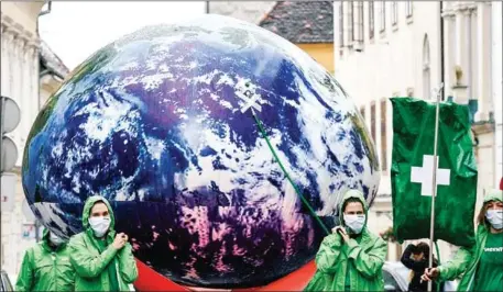  ?? AFP ?? Greenpeace activists carry a giant balloon representi­ng planet Earth which is connected to an infusion in Zagreb, Croatia, last year.