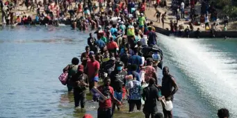  ?? AP file ?? DANGEROUS PATH: Haitian migrants use a dam to cross between the United States and Mexico last month in Del Rio, Texas.