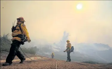  ?? MARIOTAMA / Getty Images ?? Firefighte­rs work during the Silverado Fire in Irvine, Calif., on Monday in Orange County.