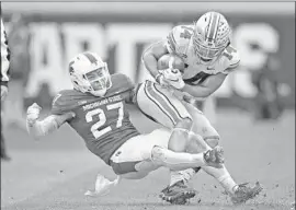  ?? Gregory Shamus Getty Images ?? K.J. HILL of Ohio State battles for yards after a second-half catch while being tackled by Michigan State’s Khari Willis. The Buckeyes pulled away for the win.