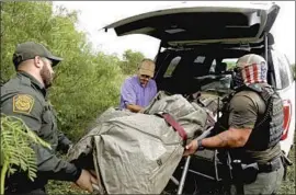  ??  ?? U.S. BORDER PATROL Agent Matthew Mercado, left, funeral director Alonzo Rangel and Brooks County Sheriff ’s Deputy Raul Narvaez load the remains of Yoel Nieto Valladares into an SUV after Rangel zipped the body bag, above.