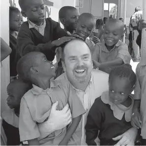  ?? Courtesy Greg Eubanks via AP ?? ■ This 2011 photo provided by Greg Eubanks, CEO of WACAP adoption agency in Washington state, shows him surrounded by students from a community elementary school in Nairobi, Kenya.