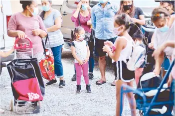  ?? — AFP photos ?? The four-year old daughter of Be y from Ecuador, stands during a food distributi­on in Queens in New York City.