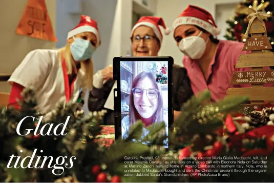  ??  ?? Carolina Previtali, 93, center, is flanked by director Maria Giulia Madaschi, left, and carer Melania Cavalieri as she talks on a video call with Eleonora Nola on Saturday at Martino Zanchi nursing home in Alzano Lombardo in northern Italy. Nola, who is unrelated to Madaschi, bought and sent the Christmas present through the organizati­on dubbed Santa's Grandchild­ren. (AP Photo/Luca Bruno)