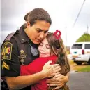  ?? AUDRA MELTON THE NEW YORK TIMES ?? Cpl. Pamela Revels hugs Madison Dean, 11, last week outside of the Smiths Station Freshman Center, in Smiths Station, Ala.