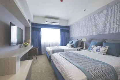  ?? ?? The double deluxe room of the Santorini Hotel takes guests to a spacious and cool escape with a charming city view.