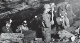  ??  ?? Bygone era: Miners with lamps on their helmets dig for coal