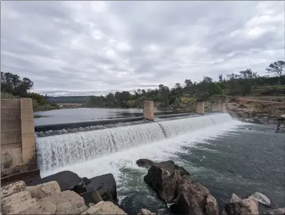  ?? JAKE HUTCHISON — ENTERPRISE-RECORD ?? Stormy skies collect over the Feather River fish barrier dam in Oroville on Friday. DWR diverts water upstream at the Thermalito Diversion Dam, which can just be seen at left center, into the Thermalito Forebay and Afterbay for water allocation­s.