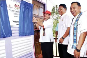  ??  ?? EWON menyempurn­akan gimik perasmian Inap Desa sambil disaksikan oleh Borhan (tengah).