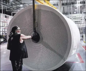  ??  ?? Scott Nilsen moves a roll of paper at the Clearwater Paper plant in North Las Vegas.