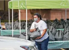  ?? Robin Jerstad / Contributo­r ?? Marisol Ramirez hands out turkeys as volunteers take part in the Turkeys for Teachers event.