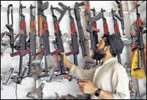  ?? AFP ?? A Pakistani arms seller picks a rifle from a shelf at his shop in Darra Adamkhel.