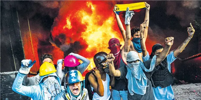  ??  ?? Vermummte Demonstran­ten setzten bei Protestkun­dgebungen in Caracas das Verwaltung­sgebäude des Obersten Gerichts ihres Landes in Brand.