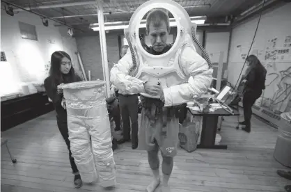  ?? Associated Press ?? ABOVE:
Erica Kim, left, an industrial and apparel design student at the Rhode Island School of Design (RISD), helps Andrzej Stewart, the chief engineerin­g officer on a year-long Mars simulation mission that ended in August, put on a new space suit...