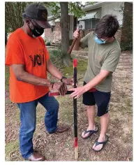  ?? (Pine Bluff Commercial/Byron Tate) ?? Jesse Milner, who attended a prayer event Saturday, hammers a cross into a yard where a 69-year-old man was found dead Thursday from gunshot wounds. Jesse Turner, one of the organizers of the event, is helping to steady the cross.