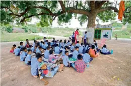  ??  ?? A teacher takes a class for the students under the shadow of a tree due to lack of classrooms at the government primary school at Middle Fort in Warangal Urban district.