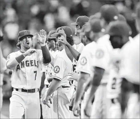  ?? Gina Ferazzi Los Angeles Times ?? COLLIN COWGILL , left, goes down the line getting high-fives during introducti­ons before the Angels’ home opener against the Royals.